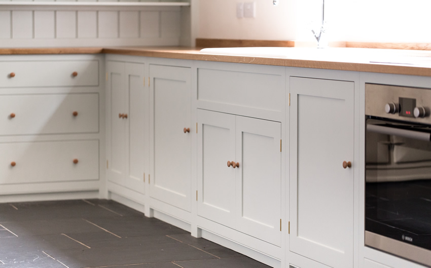 Shaker style kitchen. Birch plywood cabinets with hand painted hardwood frames (Farrow and Ball Estate Eggshell, Pale Powder).Traditional inset sink and integral dishwasher. Inset cooker hob and integral oven. 4.5m full stave oak worktop with upstand. Solid brass hinges and adjustable brass shelf supports. Solid oak dovetailed drawers with painted hardwood fronts. Hand turned beech knobs.